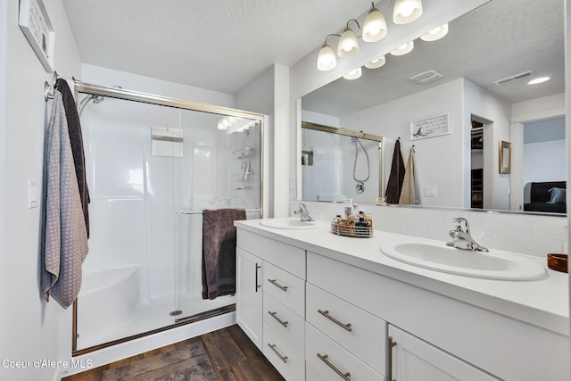 3631 N Britton Rd, Post Falls, ID 83854 - full bathroom featuring a shower stall, double vanity, wood finished floors, and a textured ceiling