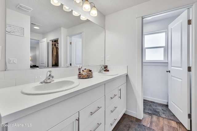 3631 N Britton Rd, Post Falls, ID 83854 - bathroom featuring double vanity, wood finished floors, a spacious closet, and decorative backsplash