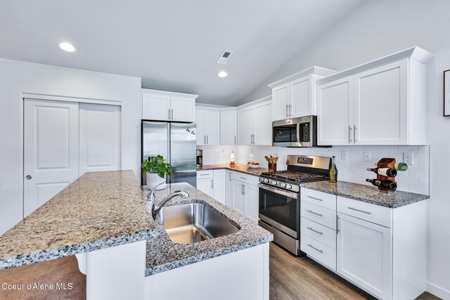 3631 N Britton Rd, Post Falls, ID 83854 - kitchen featuring appliances with stainless steel finishes, an island with sink, tasteful backsplash, white cabinets, and vaulted ceiling