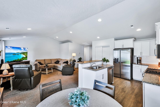 3631 N Britton Rd, Post Falls, ID 83854 - kitchen featuring stainless steel appliances, open floor plan, dark stone countertops, vaulted ceiling, and a center island with sink