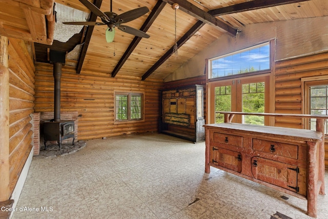 527 W Seneacquoteen, Priest River, ID 83856 - unfurnished living room with high vaulted ceiling, a wood stove, a wooden ceiling with exposed beams, rustic walls, and healthy amount of natural light