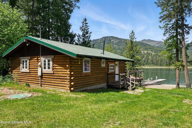 527 W Seneacquoteen, Priest River, ID 83856 - view of property exterior featuring log siding, a lawn, a water and mountain view, a metal roof, and a wooded view