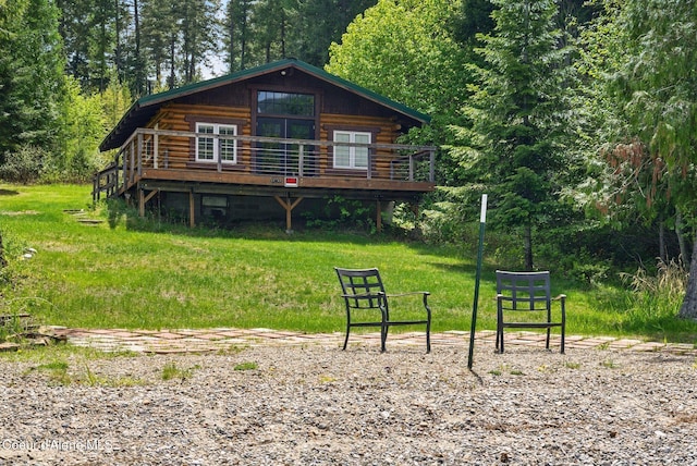 527 W Seneacquoteen, Priest River, ID 83856 - rear view of house with a wooden deck, log siding, a lawn, and a view of trees