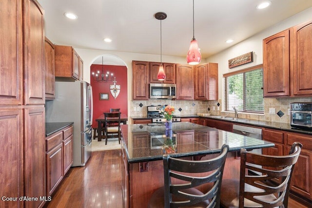 8136 Salmonberry Lp, Hayden, ID 83835 - kitchen featuring appliances with stainless steel finishes, a center island, a kitchen bar, dark wood-style flooring, and recessed lighting