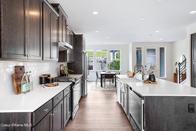 2756 W Lumber Ln Unit 7, Coeur Dalene, ID 83814 - kitchen featuring appliances with stainless steel finishes, dark brown cabinetry, wood finished floors, an island with sink, and light countertops