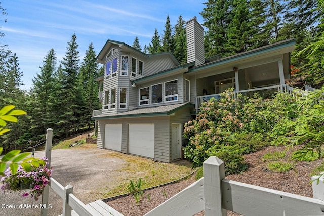 38 S Quail Run Unit B, Sandpoint, ID 83864 - view of front of house featuring a chimney, an attached garage, driveway, and a balcony
