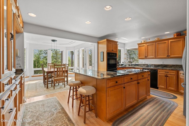 38 S Quail Run Unit B, Sandpoint, ID 83864 - kitchen with black appliances, recessed lighting, a kitchen bar, light wood-type flooring, and a kitchen island