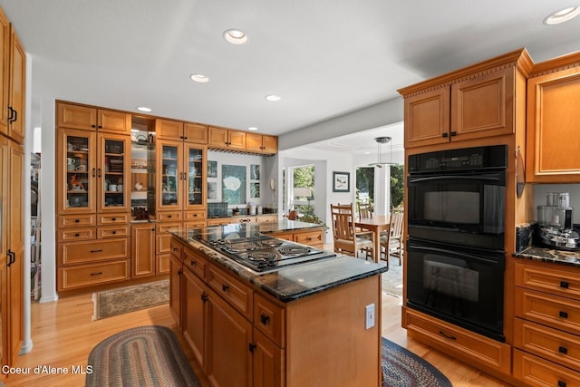 38 S Quail Run Unit B, Sandpoint, ID 83864 - kitchen with stovetop with downdraft, light wood finished floors, a kitchen island, brown cabinets, and dark stone counters
