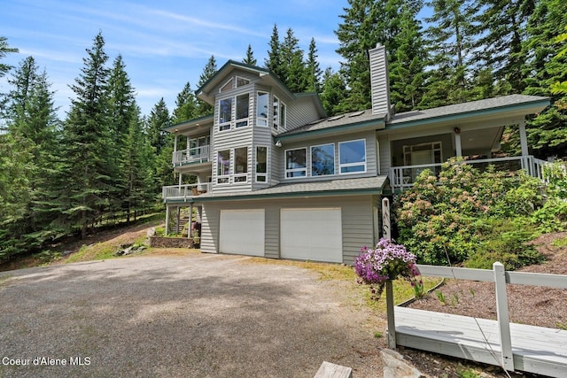 38 S Quail Run Unit B, Sandpoint, ID 83864 - view of front of home with a balcony, a chimney, driveway, an attached garage, and stairs