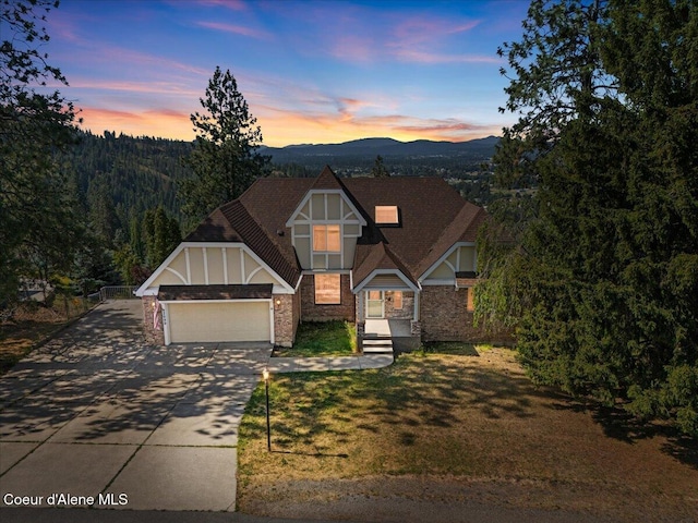 2699 E Packsaddle Dr, Coeur Dalene, ID 83815 - tudor house with an attached garage, concrete driveway, a mountain view, and stone siding