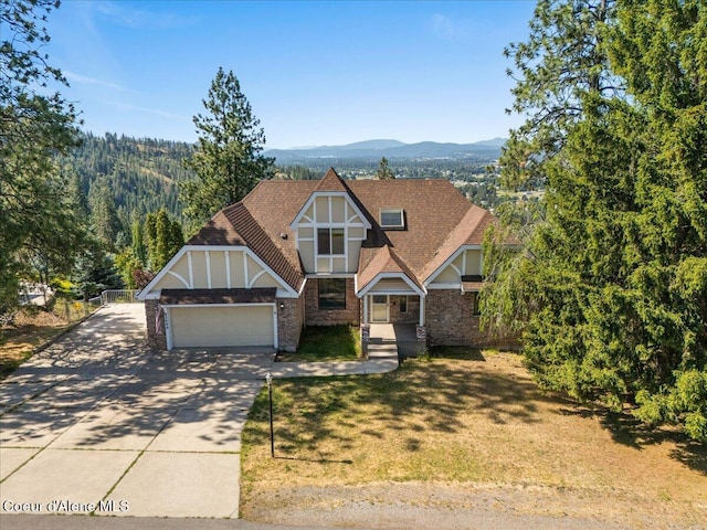 2699 E Packsaddle Dr, Coeur Dalene, ID 83815 - tudor-style house featuring a garage, driveway, brick siding, and a mountain view