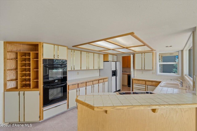 2699 E Packsaddle Dr, Coeur Dalene, ID 83815 - kitchen with black appliances, tile counters, a peninsula, and a breakfast bar
