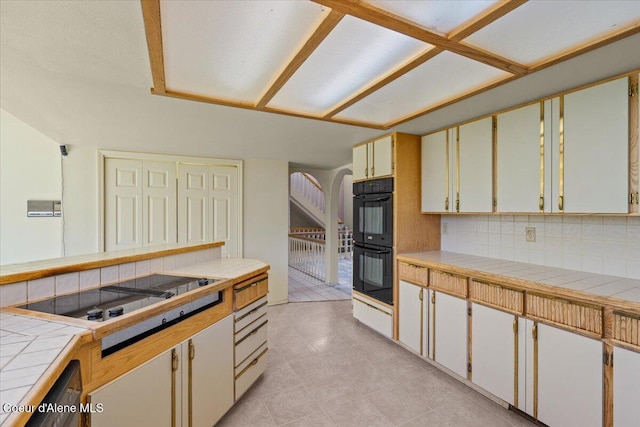 2699 E Packsaddle Dr, Coeur Dalene, ID 83815 - kitchen featuring black appliances, tile countertops, tasteful backsplash, light tile patterned floors, and arched walkways