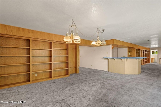 2699 E Packsaddle Dr, Coeur Dalene, ID 83815 - unfurnished living room with carpet, a chandelier, wooden walls, and a textured ceiling