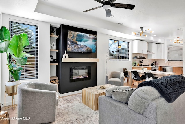 114 E Hattie, Coeur Dalene, ID 83814 - living room featuring a chandelier, a ceiling fan, light wood-type flooring, and a glass covered fireplace