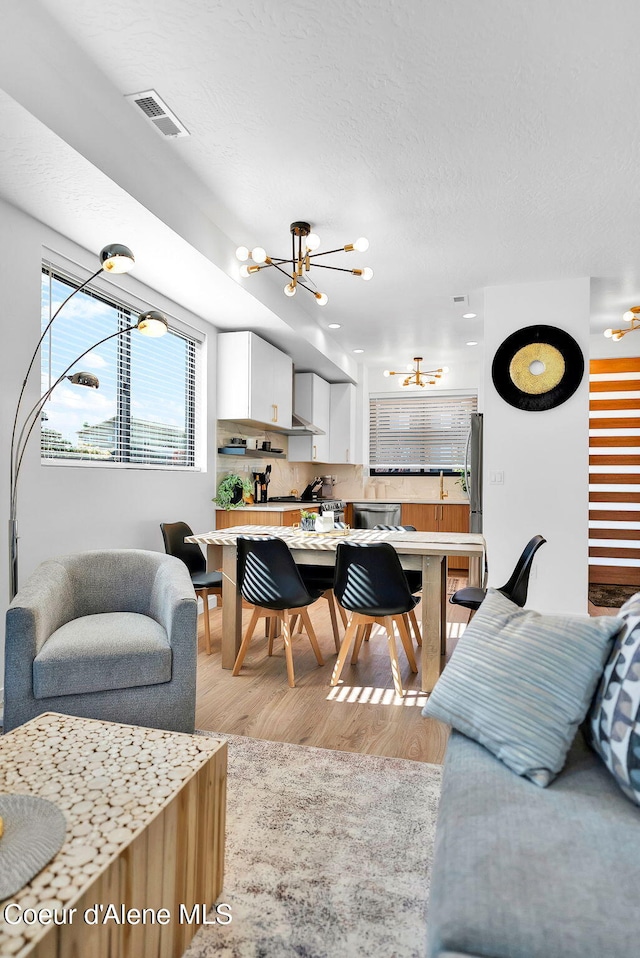 114 E Hattie, Coeur Dalene, ID 83814 - living area featuring light wood-type flooring, a chandelier, and a textured ceiling