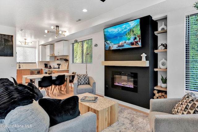 114 E Hattie, Coeur Dalene, ID 83814 - living room featuring a chandelier, light wood-style flooring, healthy amount of natural light, and a glass covered fireplace