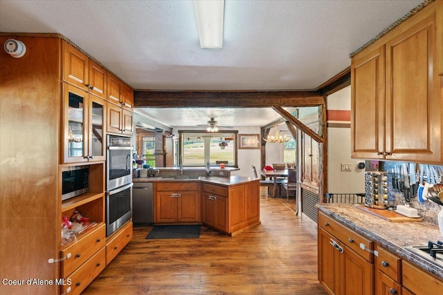 3297 Minaloosa Valley Rd, Plummer, ID 83851 - kitchen featuring appliances with stainless steel finishes, a peninsula, dark wood-style flooring, brown cabinetry, and glass insert cabinets