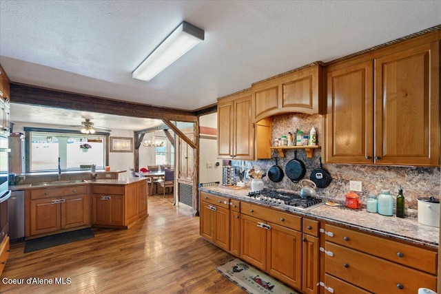 3297 Minaloosa Valley Rd, Plummer, ID 83851 - kitchen with stainless steel gas cooktop, brown cabinets, wood finished floors, decorative backsplash, and a chandelier