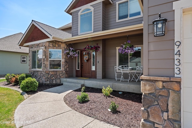9433 N Justice Way, Hayden, ID 83835 - property entrance with stone siding, a porch, and roof with shingles