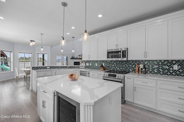 9433 N Justice Way, Hayden, ID 83835 - kitchen with stainless steel appliances, beverage cooler, a peninsula, tasteful backsplash, and light wood-style flooring