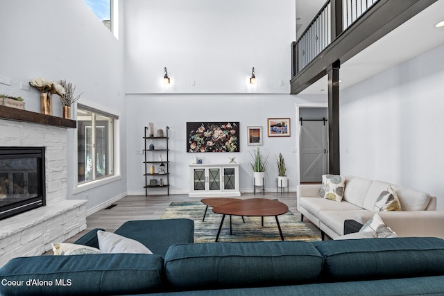 9433 N Justice Way, Hayden, ID 83835 - living room featuring a towering ceiling, a fireplace, wood finished floors, and a barn door