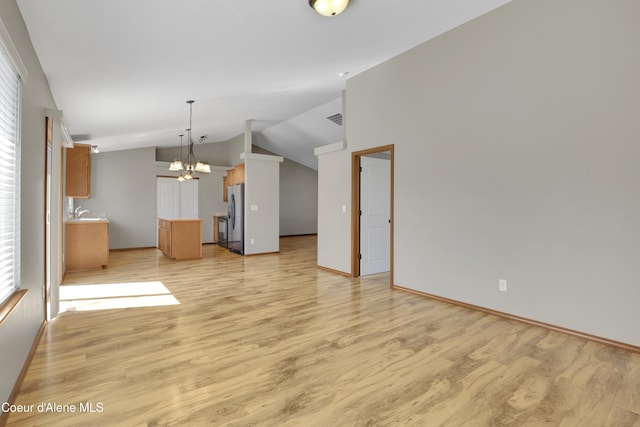 13388 N Polaris St, Rathdrum, ID 83858 - unfurnished living room with lofted ceiling, light wood-style flooring, and a chandelier