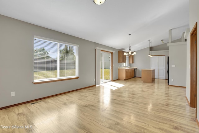 13388 N Polaris St, Rathdrum, ID 83858 - unfurnished living room featuring vaulted ceiling, light wood finished floors, and a chandelier