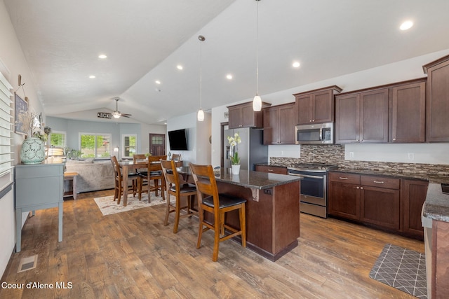 10939 N Seaside St, Hayden, ID 83835 - kitchen with stainless steel appliances, vaulted ceiling, wood finished floors, a kitchen island, and open floor plan
