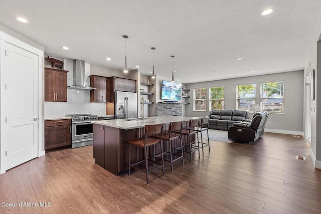 838 N Government Way, Coeur Dalene, ID 83814 - kitchen with premium appliances, wall chimney range hood, a breakfast bar, dark wood-style flooring, and a kitchen island with sink