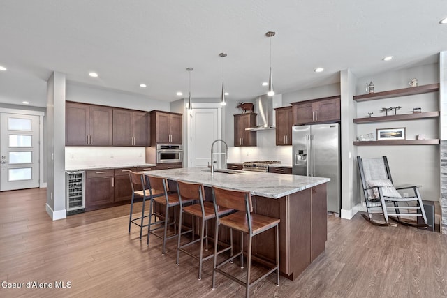 838 N Government Way, Coeur Dalene, ID 83814 - kitchen featuring high end appliances, wine cooler, wall chimney range hood, wood finished floors, and dark brown cabinetry