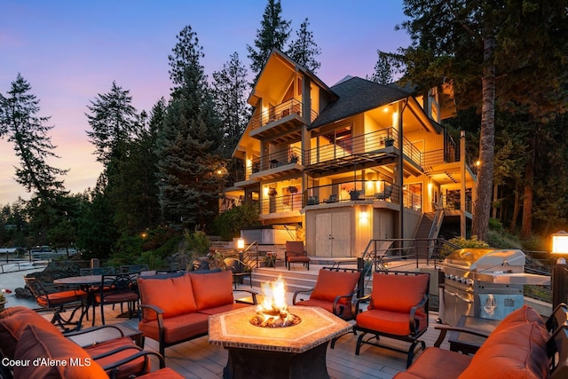 1750 W Valhalla Rd, Coeur Dalene, ID 83814 - patio terrace at dusk featuring a balcony, stairway, an outdoor living space with a fire pit, grilling area, and a wooden deck