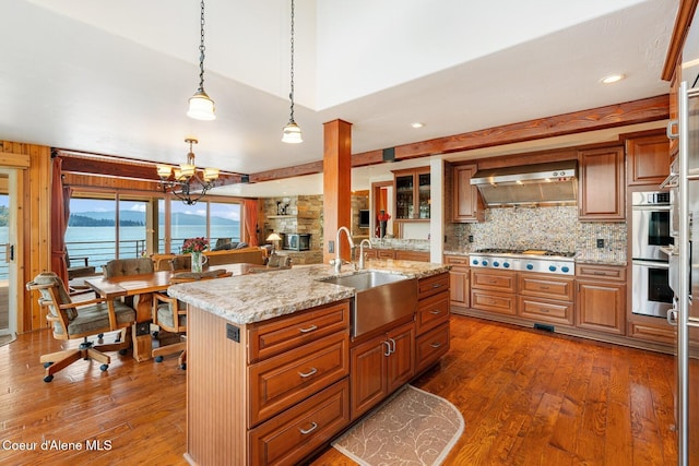 1750 W Valhalla Rd, Coeur Dalene, ID 83814 - kitchen featuring stainless steel appliances, hardwood / wood-style flooring, tasteful backsplash, extractor fan, and brown cabinetry