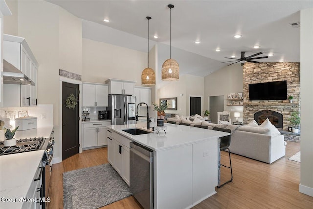 388 Wyatt Ln, Spirit Lake, ID 83869 - kitchen featuring stainless steel appliances, open floor plan, wall chimney range hood, ceiling fan, and white cabinets