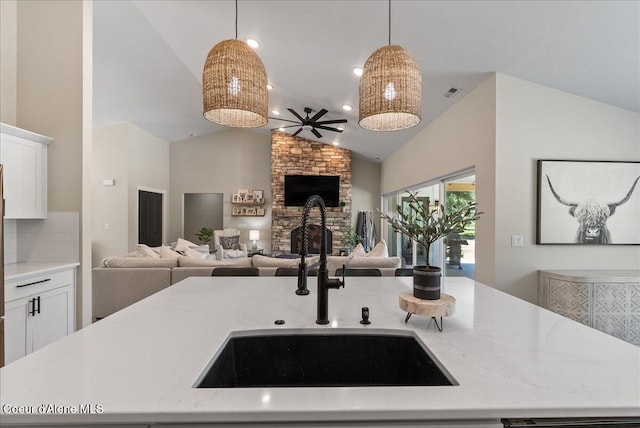 388 Wyatt Ln, Spirit Lake, ID 83869 - kitchen featuring open floor plan, lofted ceiling, hanging light fixtures, white cabinets, and light stone countertops