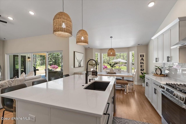 388 Wyatt Ln, Spirit Lake, ID 83869 - kitchen with stainless steel range with gas stovetop, light wood-style floors, a center island with sink, a kitchen breakfast bar, and open floor plan