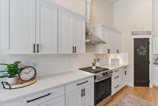 388 Wyatt Ln, Spirit Lake, ID 83869 - kitchen featuring gas stove, wall chimney range hood, white cabinetry, light countertops, and light wood-style floors