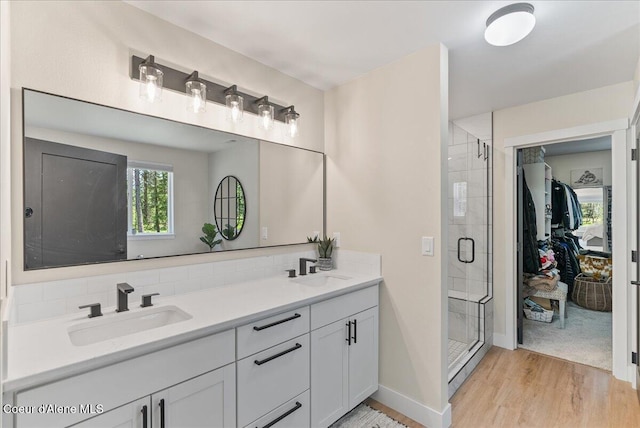 388 Wyatt Ln, Spirit Lake, ID 83869 - full bathroom with a stall shower, wood finished floors, a spacious closet, double vanity, and tasteful backsplash