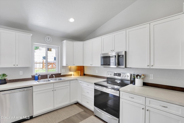 67 Bingham Way, Priest River, ID 83856 - kitchen featuring stainless steel appliances, lofted ceiling, light countertops, white cabinetry, and light wood-style floors