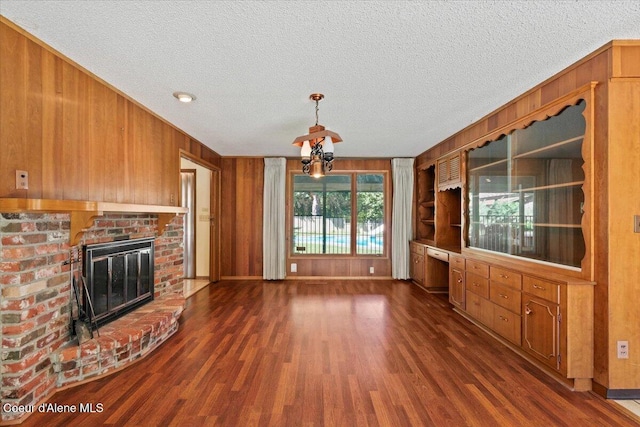 9603 N Strahorn Rd, Hayden Lake, ID 83835 - unfurnished living room with wooden walls, a textured ceiling, dark wood-style flooring, and a fireplace