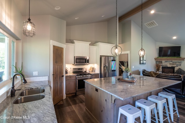23426 N Massif Rd, Rathdrum, ID 83858 - kitchen featuring appliances with stainless steel finishes, high vaulted ceiling, a kitchen island, dark wood finished floors, and light stone countertops