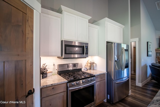 23426 N Massif Rd, Rathdrum, ID 83858 - kitchen with appliances with stainless steel finishes, tasteful backsplash, dark wood-style flooring, white cabinetry, and high vaulted ceiling