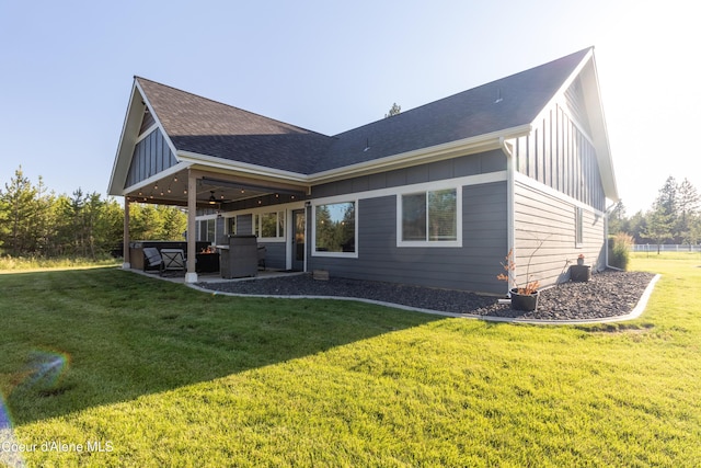 23426 N Massif Rd, Rathdrum, ID 83858 - rear view of house with board and batten siding, ceiling fan, a patio area, a lawn, and a shingled roof