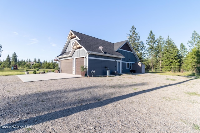 23426 N Massif Rd, Rathdrum, ID 83858 - view of side of home with board and batten siding, concrete driveway, a garage, and a shingled roof