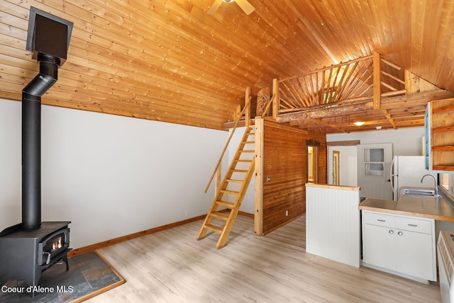 1053 Upper Pack River Rd, Sandpoint, ID 83864 - kitchen featuring a wood stove, light wood-style flooring, lofted ceiling, wood ceiling, and white cabinets