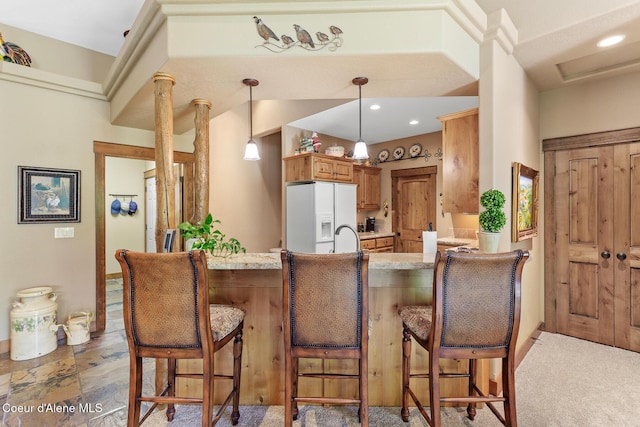 11477 N Rocking R Rd, Hayden, ID 83835 - kitchen featuring white refrigerator with ice dispenser, a peninsula, decorative light fixtures, light stone counters, and a kitchen breakfast bar