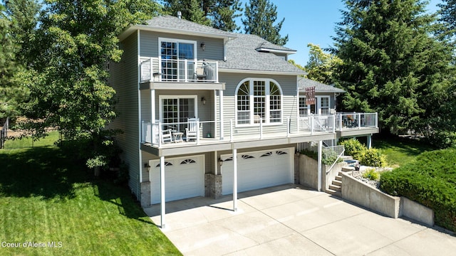 5570 E Shoreline Dr, Post Falls, ID 83854 - view of front facade featuring an attached garage, a balcony, concrete driveway, a front lawn, and roof with shingles