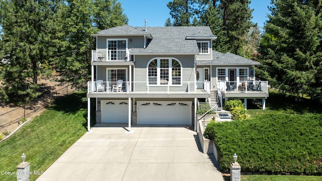 5570 E Shoreline Dr, Post Falls, ID 83854 - view of front facade with driveway, a balcony, a garage, a shingled roof, and a front lawn