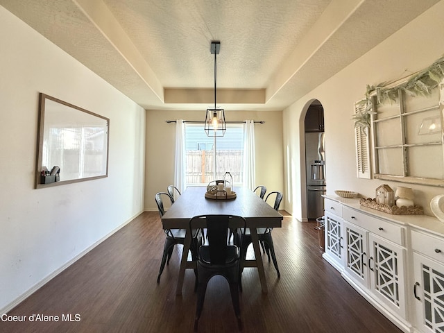 2699 E Thrush Dr, Post Falls, ID 83854 - dining room featuring a tray ceiling, arched walkways, dark wood finished floors, and a textured ceiling