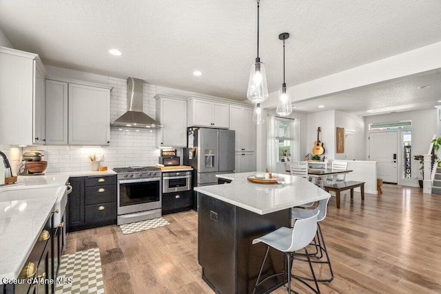 1839 N Skagit Dr, Post Falls, ID 83854 - kitchen featuring stainless steel appliances, wall chimney exhaust hood, a breakfast bar, a kitchen island, and tasteful backsplash